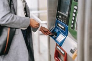 faceless woman inserting credit card into subway ticket machine