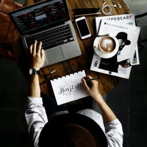 person sitting facing laptop computer with sketch pad